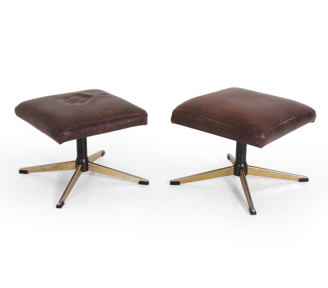 PAIR OF SCANDINAVIAN LEATHER OTTOMAN STOOLS 1960S: Dimensions: H 15" x W 24" x D 24". Condition: Oxidation to bases. Scuffs and rubs to leather. Tobacco odor. Wear consistent with age and use.