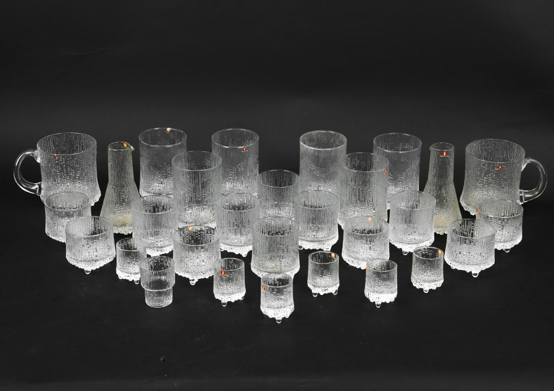 TAPIO WIRKKALA FOR IITTALA GLASS GROUPING: (29) Glasses total. Most with labels. Dimensions: (Largest) H 4.5" x W 3.75" x D 5.25" Condition: One mug with crack near handle.