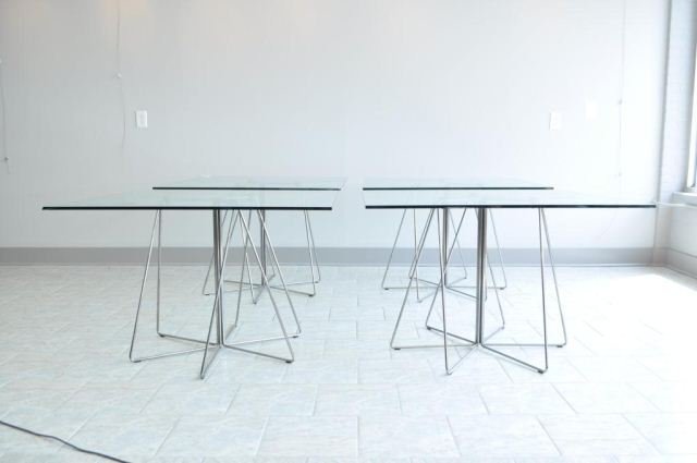 FOUR ITALIAN METAL & GLASS TABLES: Set of 4 Italian metal and glass tables. Condition: 3 have chips to the glass 1 is excellent. Bases are excellent. Dimensions: H 28" Base: 33" on bottom Glass: 42" square From "the seedhouse" NYC