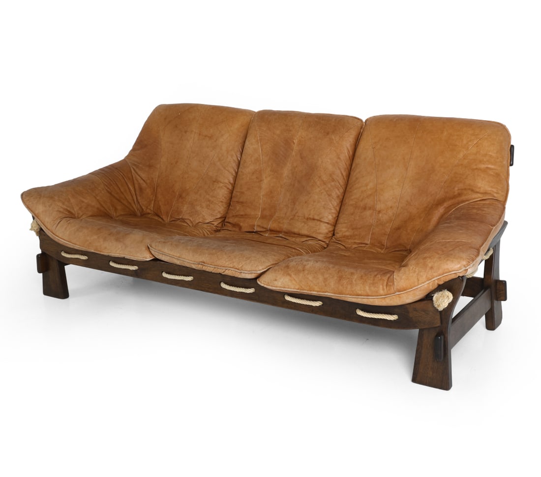 SCANDINAVIAN BRUTALIST LEATHER & OAK SOFA C. 1970S: Dimensions: H 35" x W 81" x D 32" x SH 17". Condition: Scuffs, rubs, and fading to leather. Scuffs to wood. Wear consistent with age and use. PT109