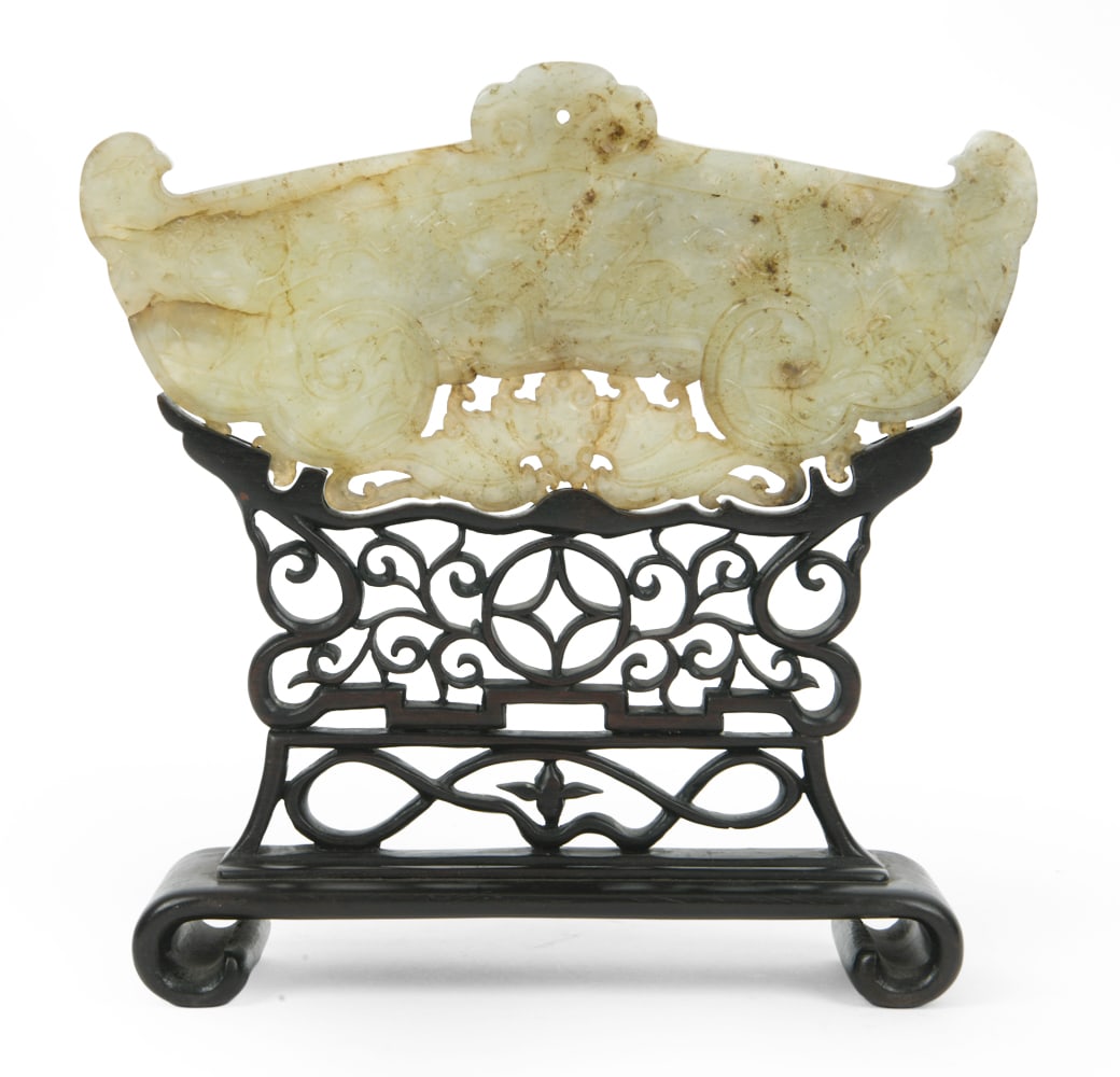 CHINESE CARVED JADE PLAQUE: Pale green nephrite jade carving on wooden stand. Dimensions: H 8" x W 8" (on stand) Condition: Cracks and scratches. Areas of discoloration to surface. Wear consistent with age.