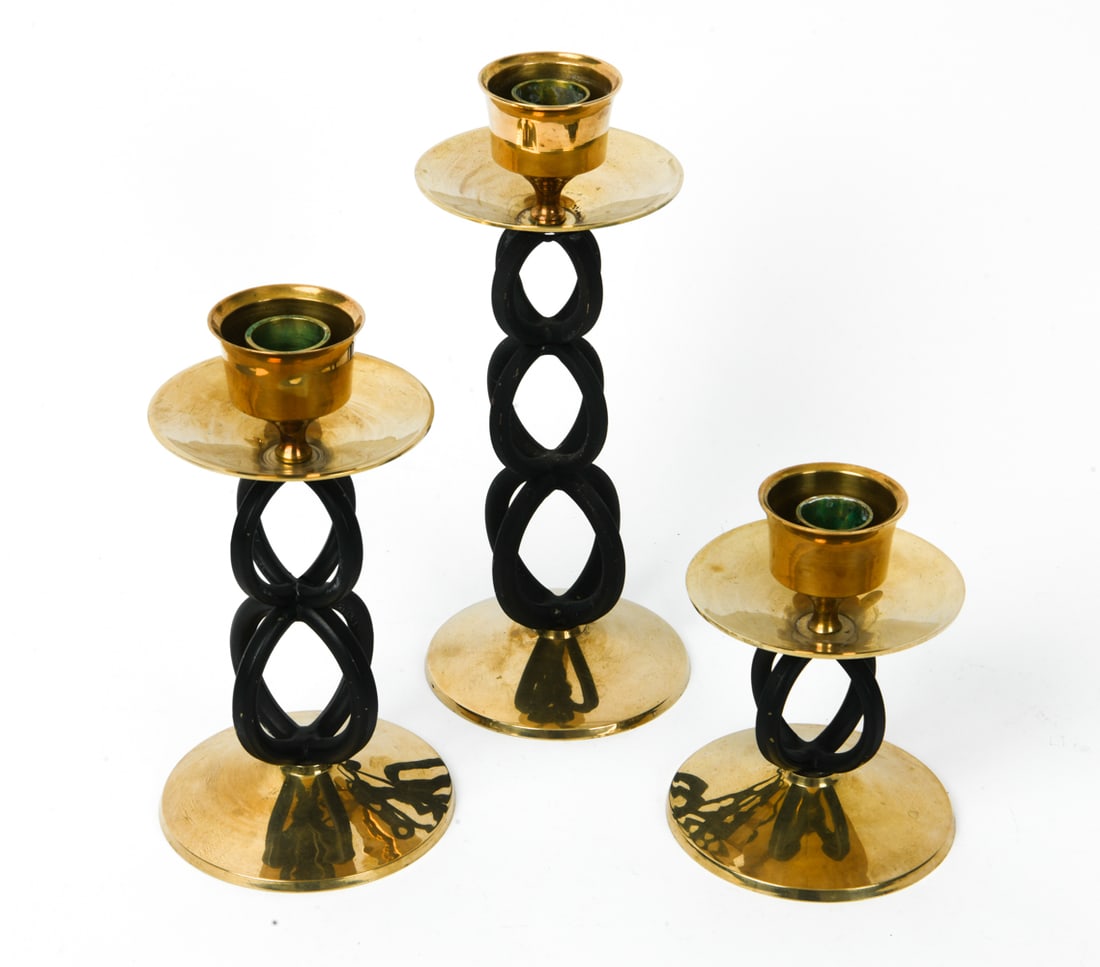 MAGASIN BRASS CANDLESTICK GROUPING: Tagged underneath. Dimensions: Tallest H 9.5" x Dia. 4". Condition: Light scuffs. Wax residue. Wear consistent with age and use.