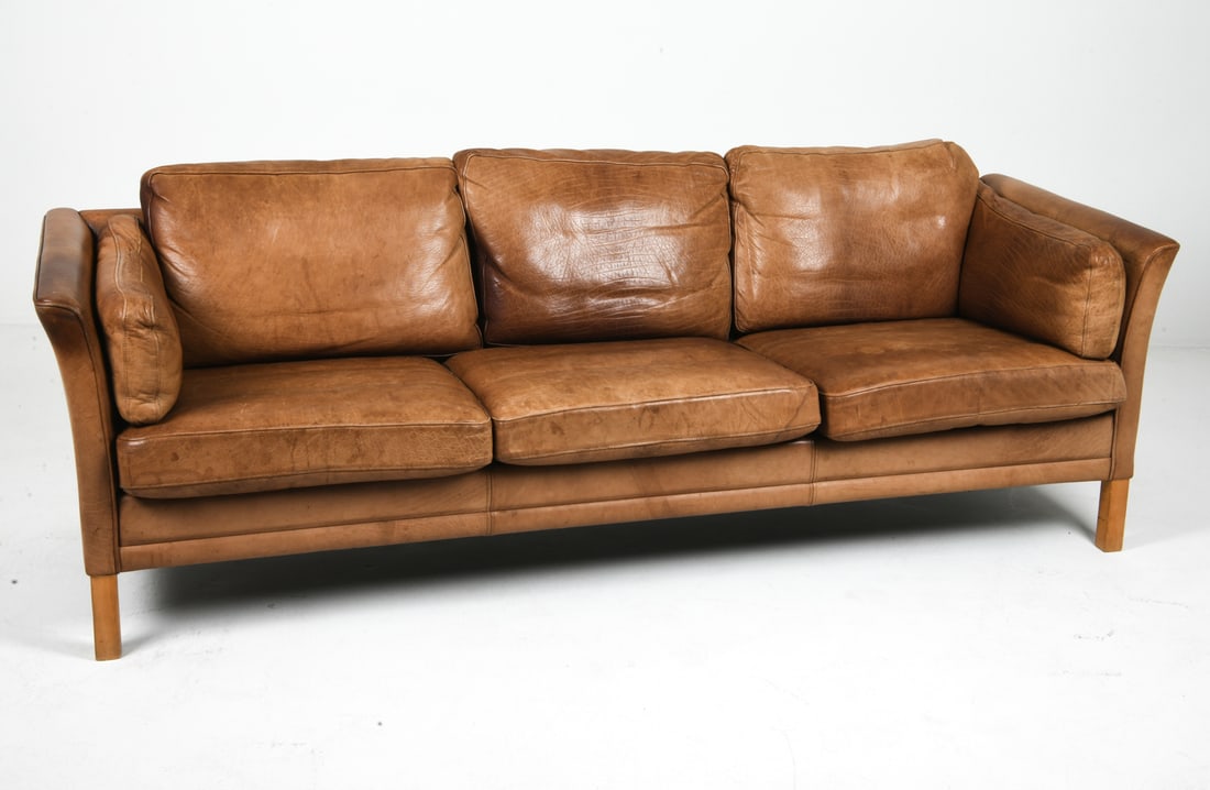 MOGENS HANSEN DANISH LEATHER SOFA C. 1960S: Brown leather sofa with beech legs. Apparently unmarked. Denmark, circa 1960s. Dimensions: H 26" x W 82" x D 28" x SH 15". Condition: Slight sun fading, few scuffs and rubs to leather. Wear