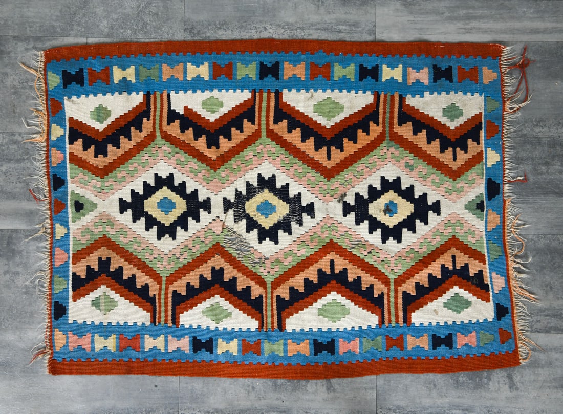 VINTAGE FLATWEAVE WOOL RUG: Wool rug with colorful geometric designs and fringe. Dimensions: L 60" x W 38.75". Condition: Loose threads in design to center. Minor losses to fringe. Wear consistent with age and use.