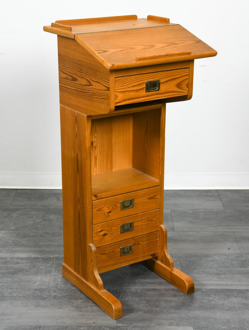 SWEDISH PINE PODIUM STANDING LECTERN DESK C. 1970S: Pine podium lectern desk with brass pulls. Sweden, circa 1970s. Dimensions: H 45.5" x W 20" x D 20.5". Condition: Scuffs, dings, and scratches, mostly to base. Rubs and oxidation to brass pulls.