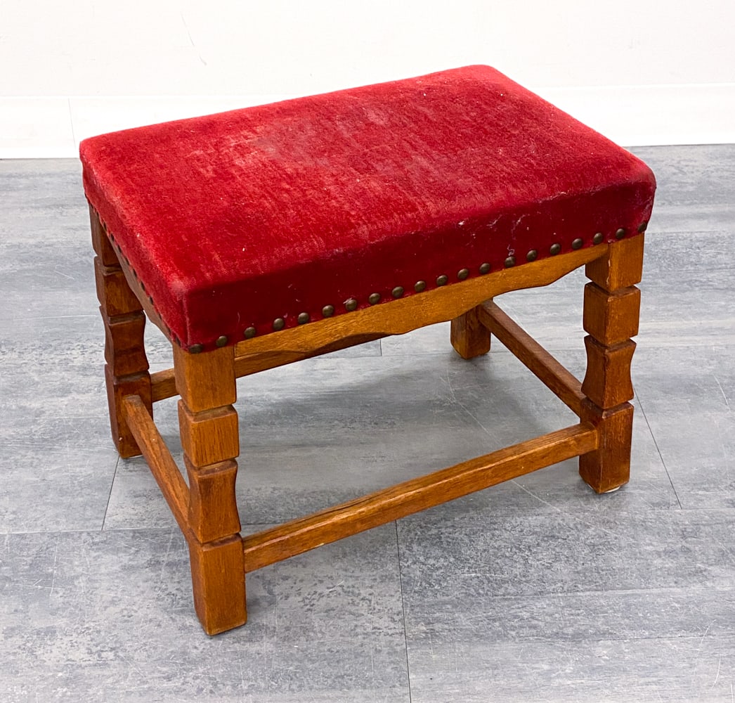 DANISH OAK OTTOMAN FOOTSTOOL C. 1970S: Oak frame with turned legs. Red fabric upholstery with brass tacks accents. Denmark, circa 1970s. Dimensions: H 15.25" x W 18" x D 12.5". Condition: Balding to fabric on seat and edges. Wear