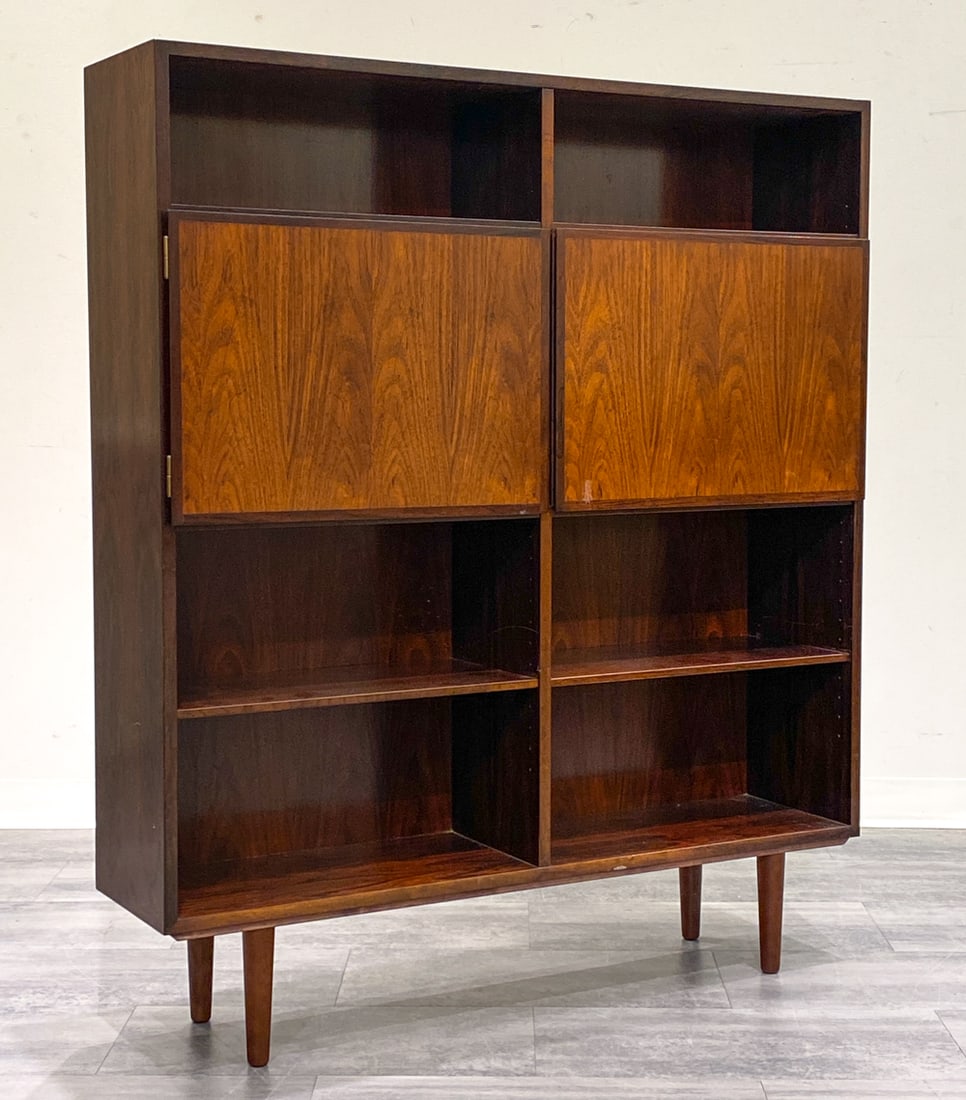 OMANN JUN DANISH ROSEWOOD BOOKCASE C. 1960S: Two center doors and shelves. Marked to back. Denmark, circa 1960s. Dimensions: H 55.5" x W 47.5" x D 11.5" Condition: Wear consistent with age and use. Couple of minor scuffs to shelves.