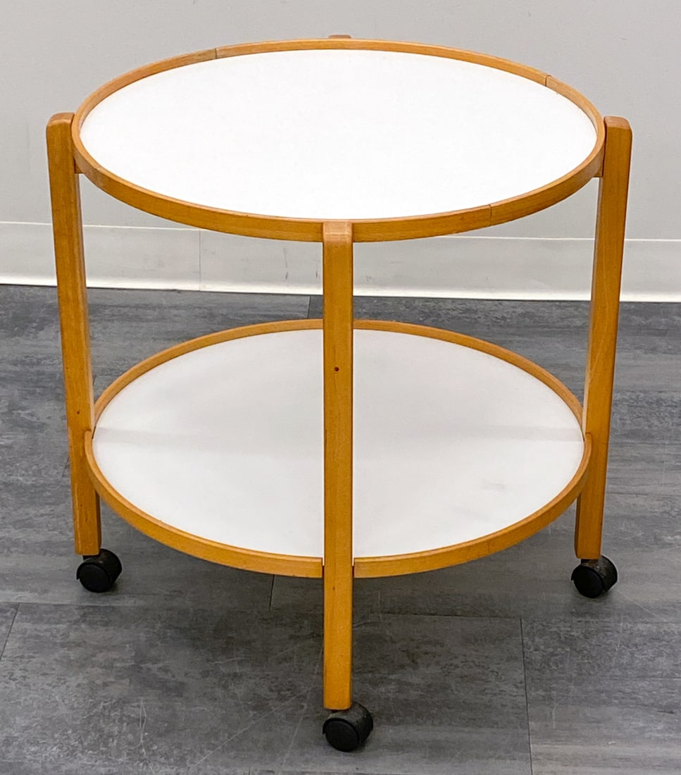 HANS BOLLING STYLE DANISH BEECH BAR CART C. 1970S: Featuring two laminate trays and beech frame with casters. Denmark, circa 1970s. Dimensions: H 24" x Dia 23" Condition: Wear consistent with age and use. Minor scuffs. Stress crack to top tray at join