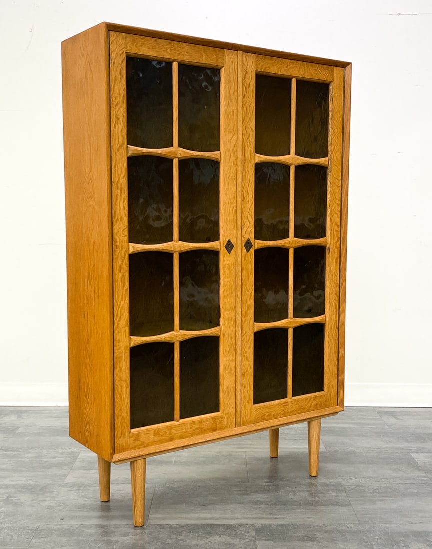 DANISH OAK BOOKCASE CABINET C. 1970S: Includes key. Two glass doors and adjustable shelves inside the unit. Marked to back. Denmark, circa 1970s. Dimensions: H 54.25" x W 34.75" x D 11" Condition: Wear consistent with age and use. Fading