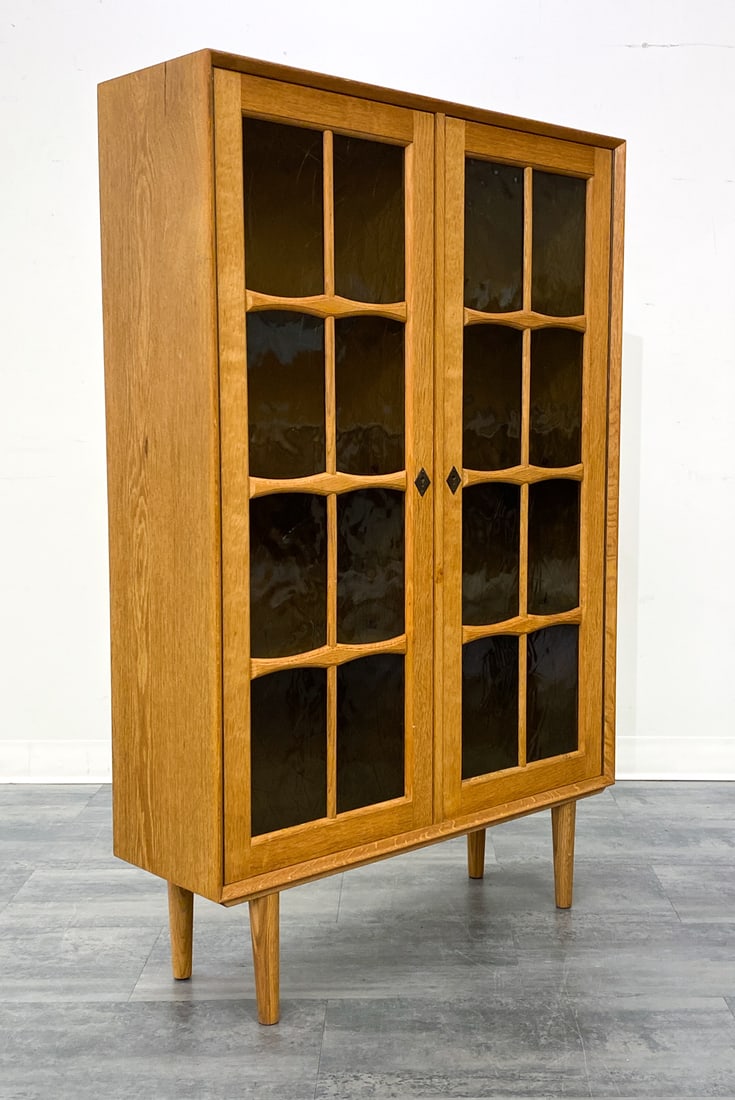 DANISH OAK BOOKCASE CABINET C. 1970S: Includes key. Two glass doors and adjustable shelves inside the unit. Marked to back. Denmark, circa 1970s. Dimensions: H 54.25" x W 34.75" x D 11" Condition: Wear consistent with age and use. Minor