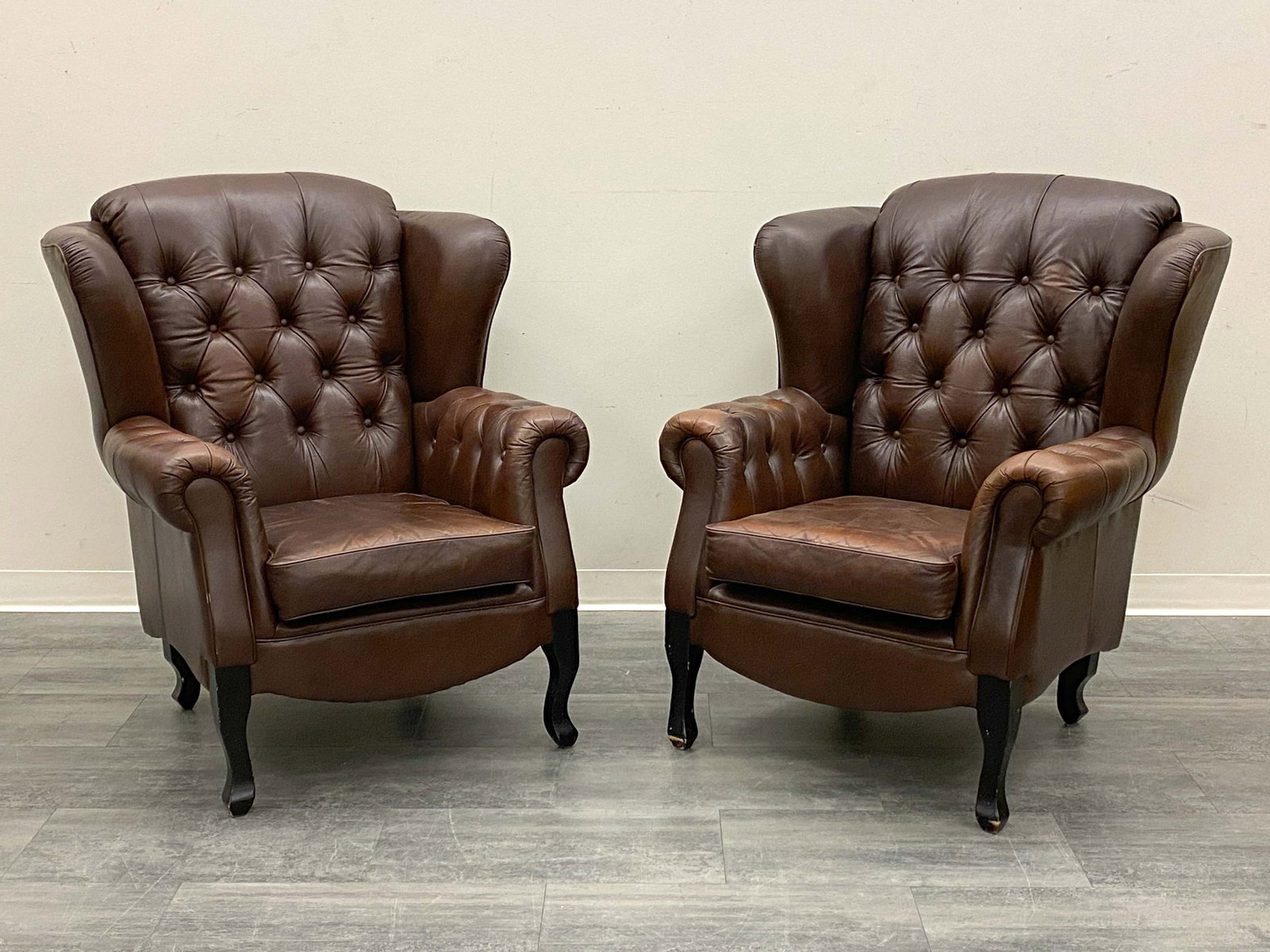 PAIR OF CHESTERFILED STYLE LEATHER LOUNGE CHAIRS: Tufted leather upholstered chairs. European, circa 1960s. Dimensions: H 43" x W 47" x D 28" x SH 18" Condition: Wear consistent with age and use. Paint loss to legs. Scuffs, rubs to sides and back. On