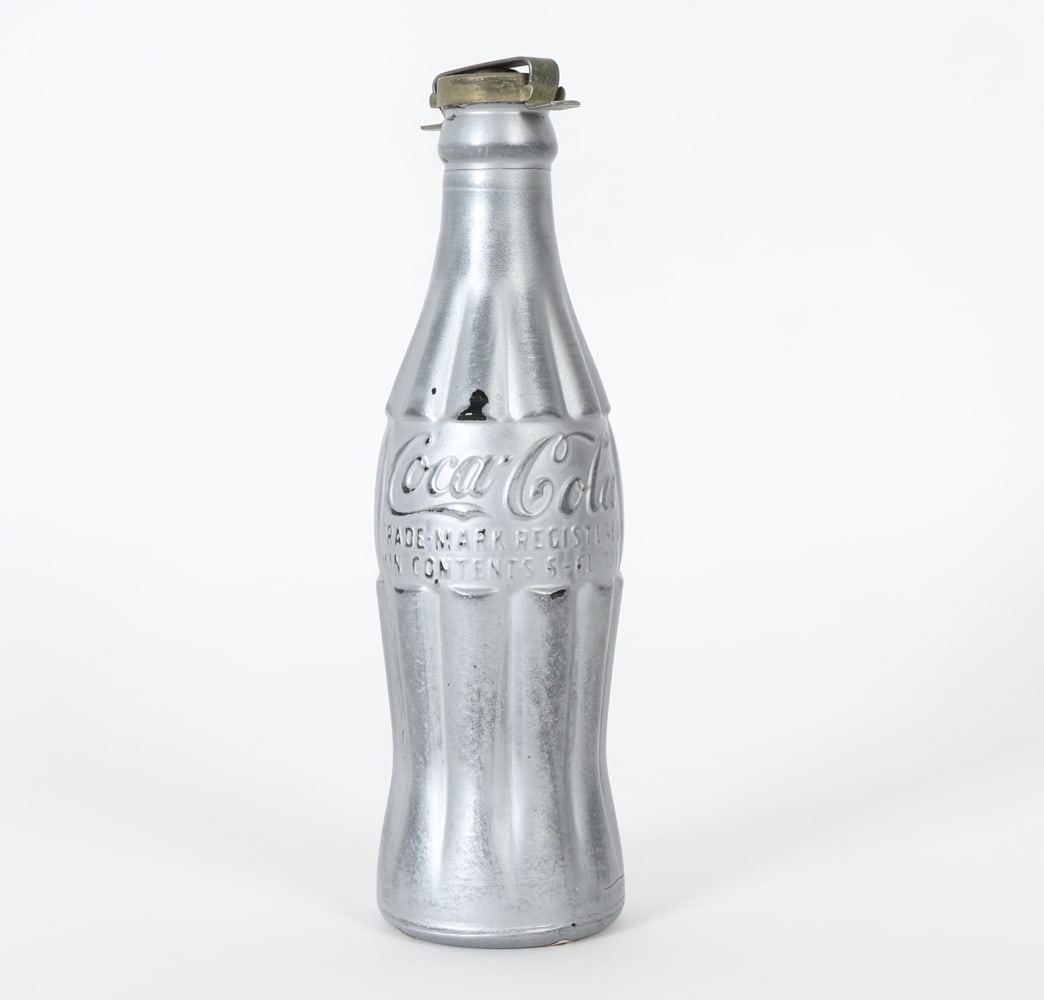 ATTR. ANDY WARHOL "YOU'RE IN" COCA COLA BOTTLE: Part of Andy Warhol's series of silver spray-painted objects. Initialed A. W. on bottle cap and a Sotheby's New York, The Andy Warhol Collection sticker on underside. Silver spray painted vintage