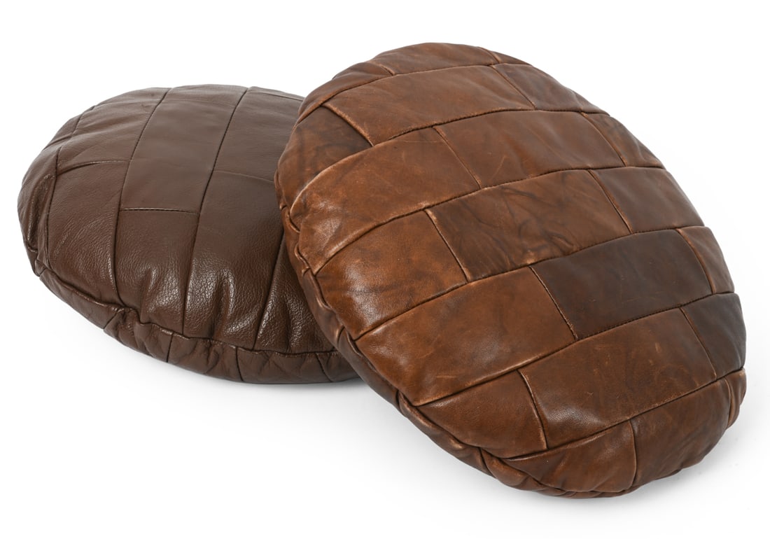 PAIR OF DE SEDE STYLE LEATHER CUSHIONS C. 1960S: Pair of round cushions with slightly differing shades of brown and patchwork leather upholstery. Dimensions: Dia 13.5" Condition: Scuffs and surface marks. Wear consistent with age and use. PU76