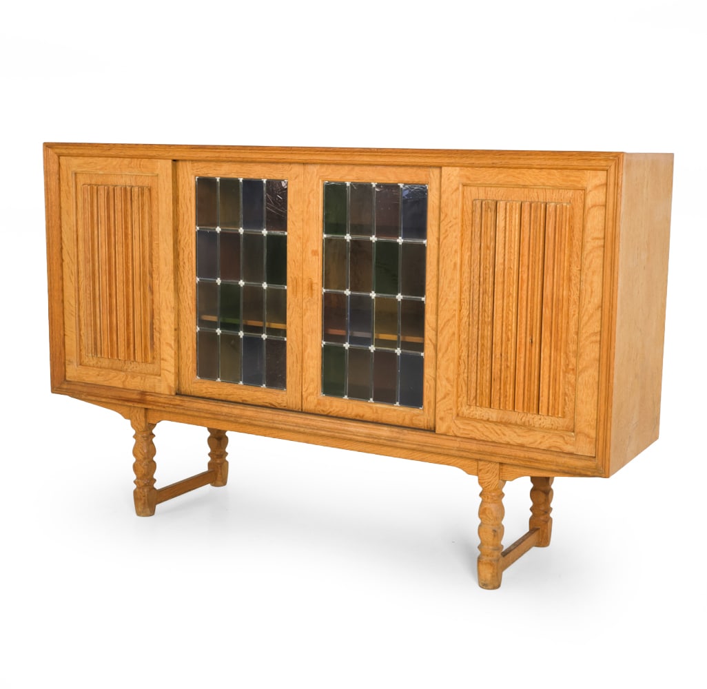 ATTR. RANDERS DANISH OAK SIDEBOARD C. 1970S: Stained glass and carved decoration to front sliding doors. Marked to backside. Denmark, circa 1970s. Dimensions: H 45 " x W 71 " x D 18.25 " Condition: Wear consistent with age and use. Water marks, 