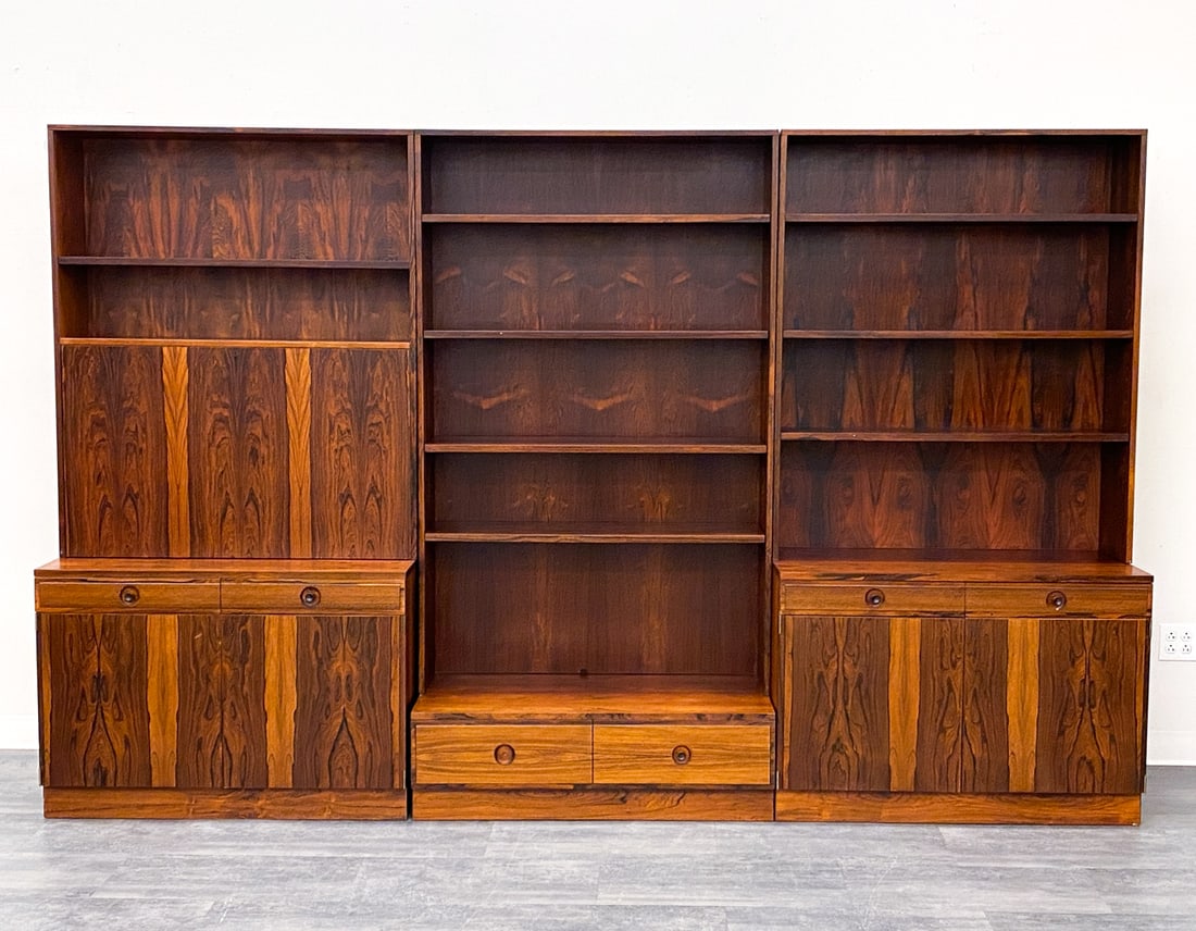 BERTIL FRIDHAGEN ROSEWOOD BOOKCASE CABINETS: Key included. (3) Bookcase cabinets in rosewood designed by Bertil Fridhagen for Bodafors. One unit features a dry bar with glass shelves and mirrored back panel. Marked inside drawer. Sweden, circa 1