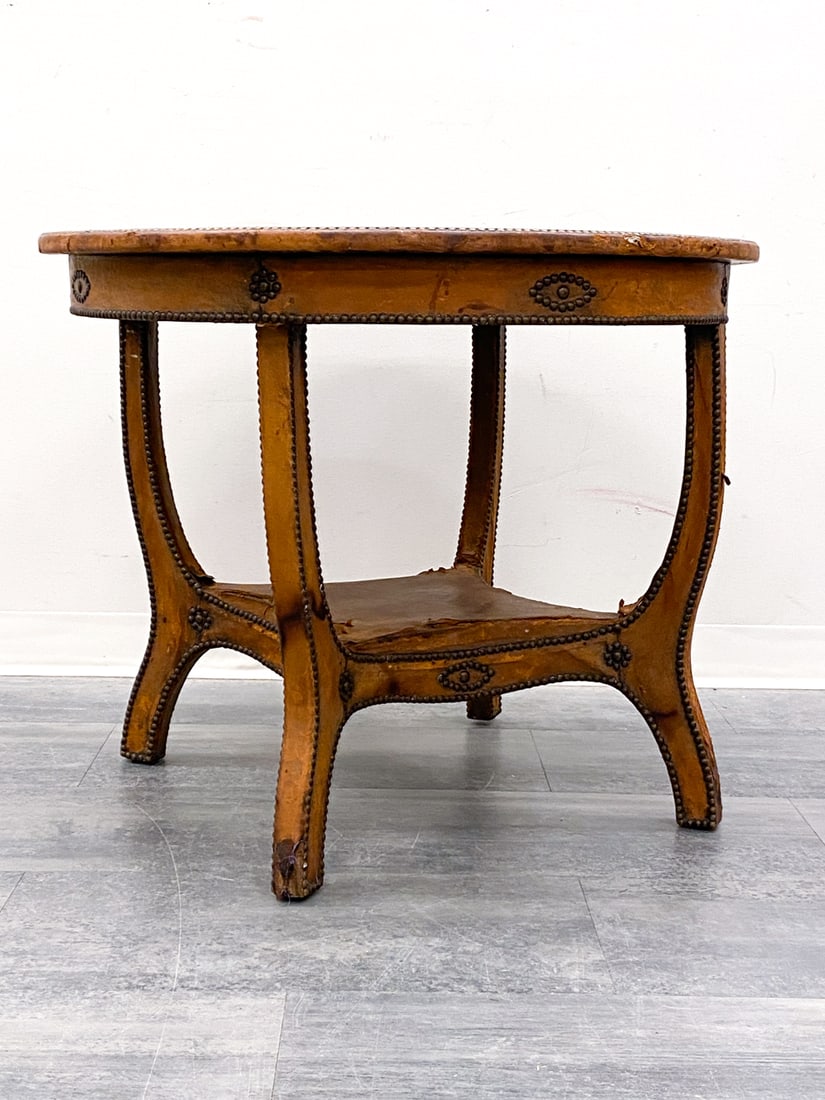 ATTR. OTTO SCHULTZ SWEDISH OAK AND LEATHER TABLE: Oak table with leather details. Sweden, circa 1930s. Dimensions: H 27.5" x Dia 33.75" Condition: Wear consistent with age and use. Scuffs, scratches, leather loss to legs. Watermarks, rubs, scratches.