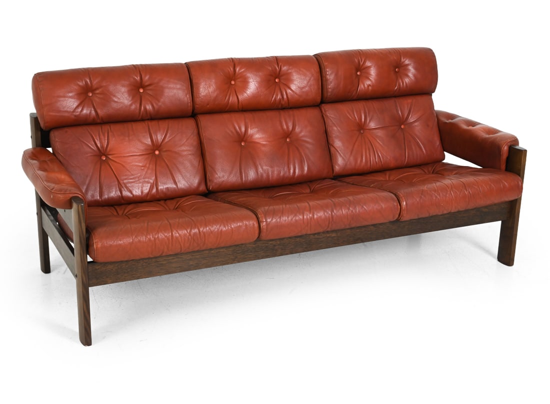 EKORNES "BRASILIA" NORWEGIAN LEATHER SOFA 1970S: Stained beech frame and tufted leather upholstery. Apparently unmarked. Norway, circa 1970s. Dimensions: H 34" x W 78" x D 34" x SH 17" Condition: Wear consistent with age and use. Soiling to back. Cr