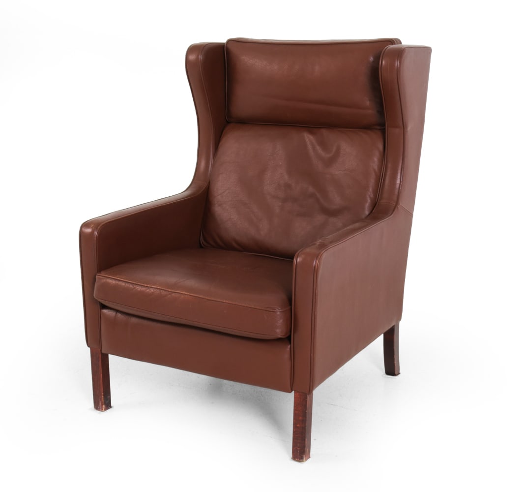 STOUBY LEATHER WINGBACK LOUNGE CHAIR C. 1960S: Marked underneath cushion. Leather with wingback design and stained beech legs. Denmark, circa 1960s. Dimensions: H 40.25" x W 29" x D 34" x SH 17" Condition: Discoloration, scuffs, wear and patina
