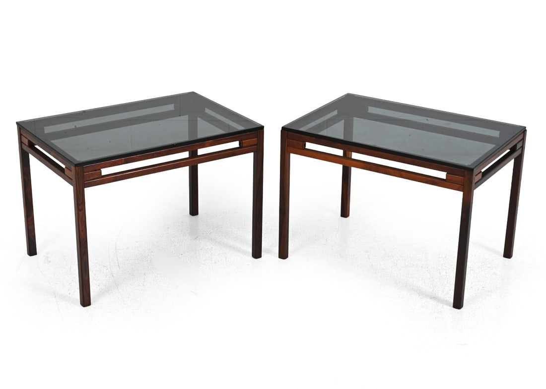PAIR WIKKELSO STYLE GLASS & ROSEWOOD SIDE TABLES: Rosewood frame and smoked glass top. Denmark, circa 1960s. Dimensions: H 18" x W 25" x D17" Condition: Discoloration. Chips to glass corner and edge. Wear consistent with age and use. 5130