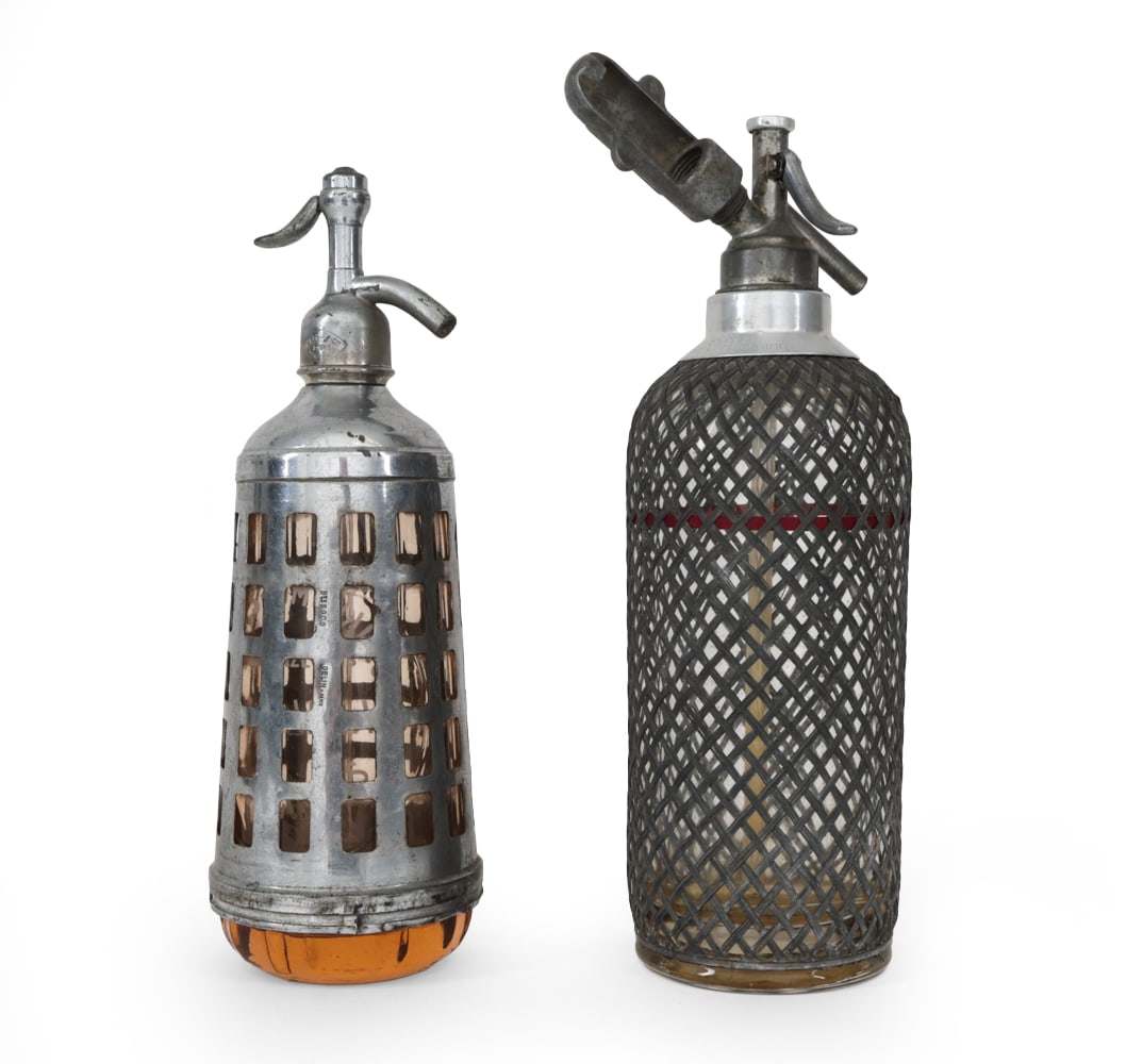 VINTAGE SPARKLETS SELTZER SODA SYPHONS C. 1920S: Metal mesh sleeve with glass bottle. Marked to handle "sparklet ". Numbered underneath. Dimensions: H 14 " x Dia 4 " Condition: Wear consistent with age and use. Antique patina and surface marks.