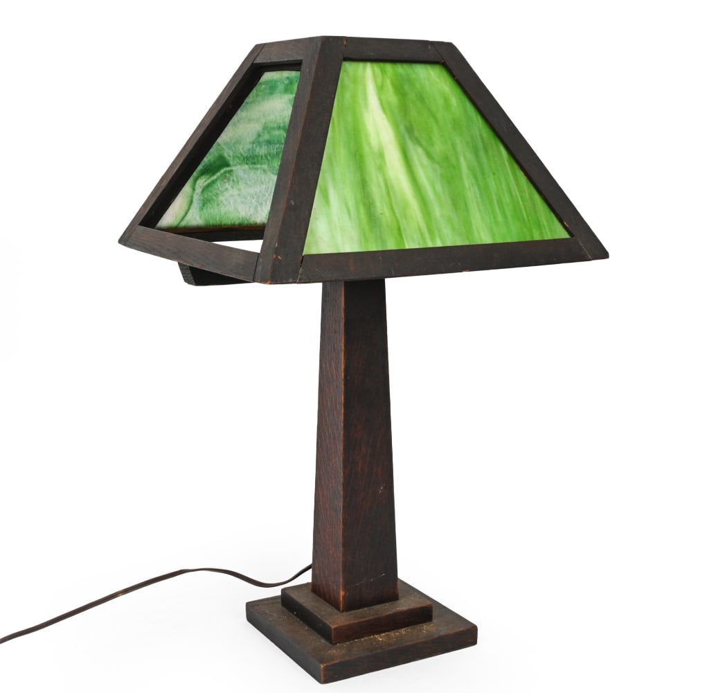 ARTS & CRAFTS OAK AND SLAG GLASS TABLE LAMP: Apparently unmarked. Dimensions: H 23" x W 13.75" x D 13.75" Condition: Lacking one glass panel. Surface wear, rubs, scratches, wear consistent with age and use. Untested.