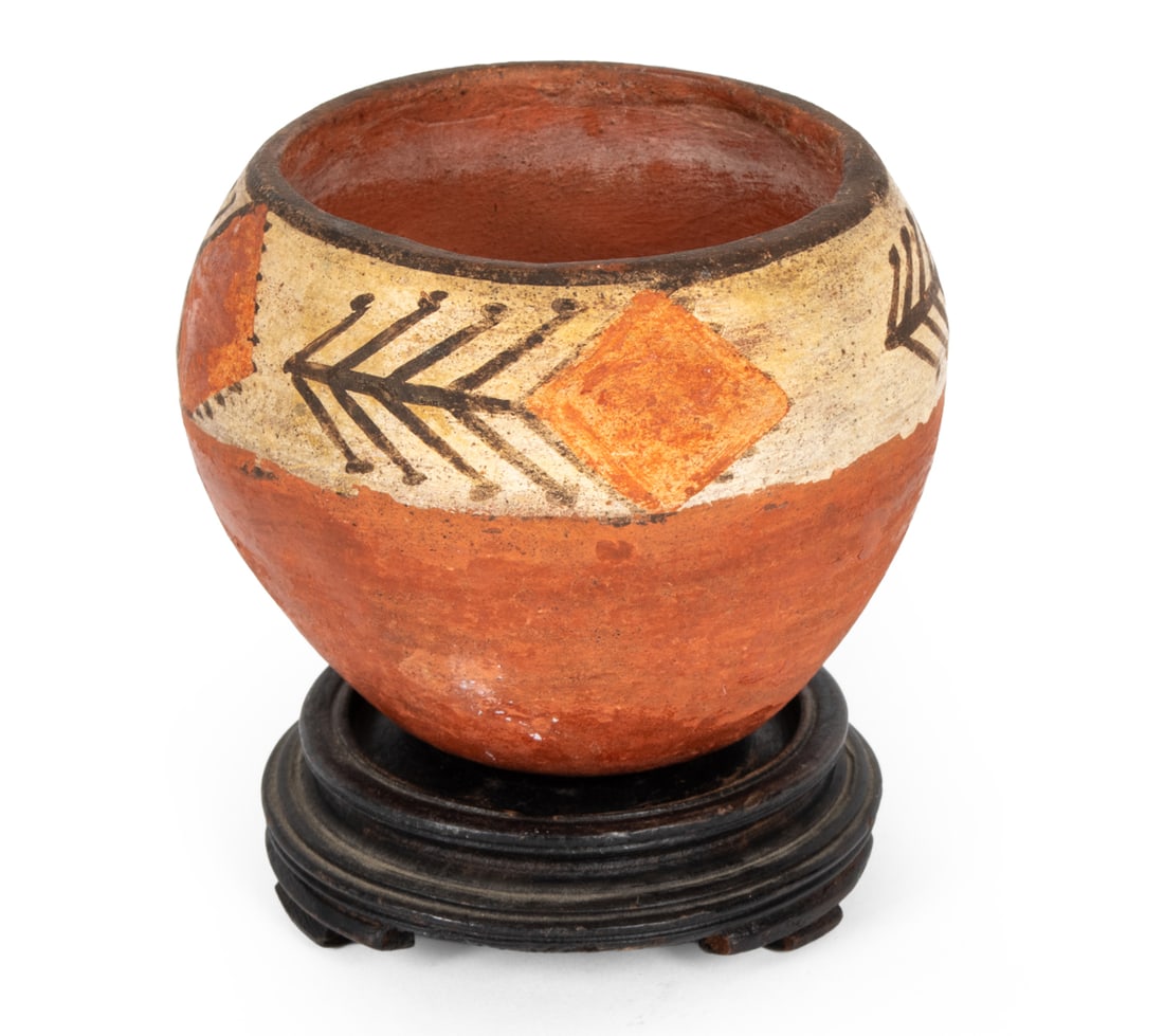 STONEWARE VESSEL ON WOODEN STAND: Terracotta vessel with painted geometric motif. Sitting on a wooden stand. Dimensions: (Vessel) H 2.25" x Dia 3" Condition: Slight rubs and surface marks.
