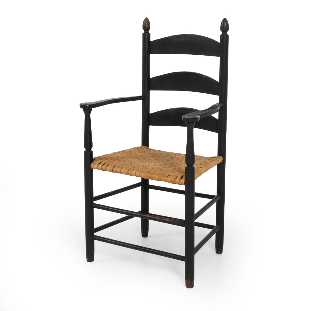NEW ENGLAND SPLINT LADDER-BACK ARMCHAIR: Ladder-back black painted frame with basket-woven splint seat and turned finials at the top posts. Dimensions: SH 17 " x H 40.5 " x W 21 " x D 16 " Condition: Wear to finish, discoloration, and