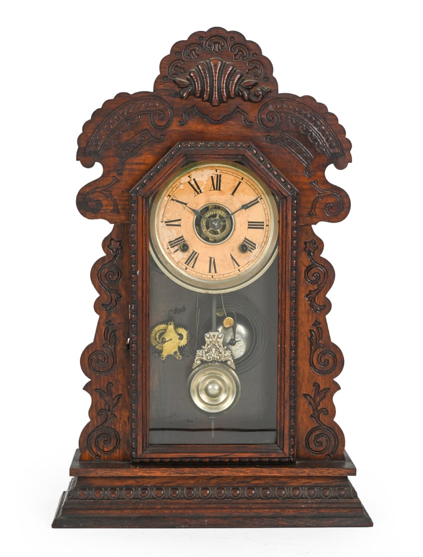 ANSONIA OAK GINGERBREAD MANTEL CLOCK C. 1890S: Marked on clock face. Intricately carved oak with metal clock components. Multiple winding keys included. Circa 1890s. Dimensions: H 22.75" x W 14.5" x D 5" Condition: Scuffs, wear of finish, and some