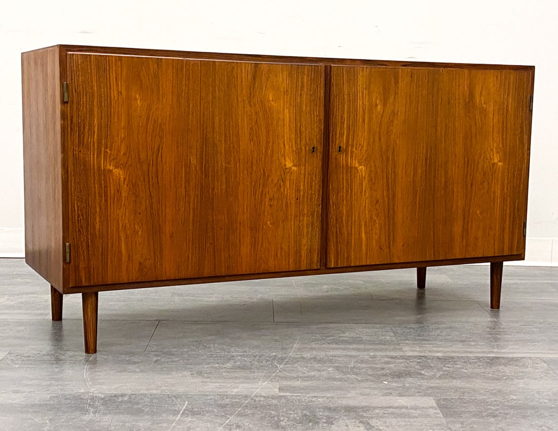 ATTR. POUL HUNDEVAD DANISH ROSEWOOD CABINET 1960S: Two-door cabinet. Includes key. In rosewood. Denmark, circa 1960s. Dimensions: H 27" x W 52" x D 18" Condition: Wear consistent with age and use. Fading to top. Scuffs, nicks, minor dings, rubs, light