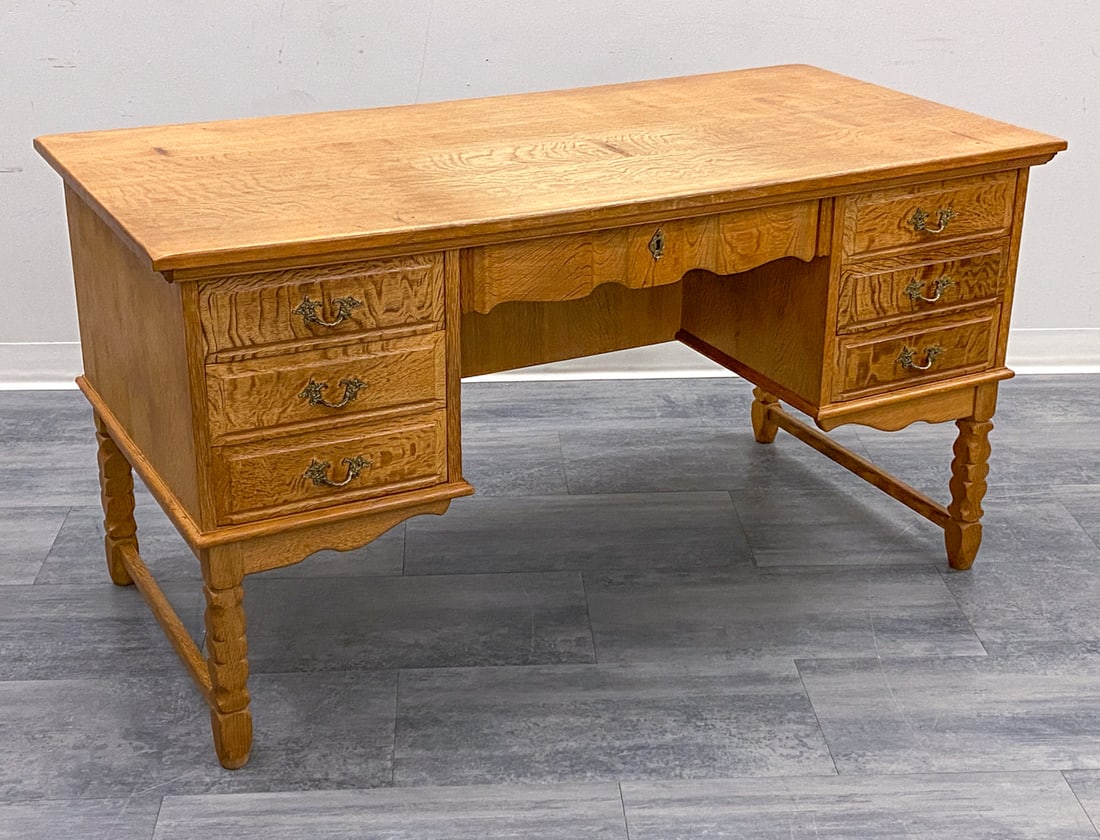 ATTR. HENNING KJAERNULF DANISH OAK WRITING DESK: Includes key. Carved oak desk with 7 drawers and brass pulls. Denmark, circa 1970s. Dimensions: H 29.5" x W 56" x D 27.75" Condition: Wear consistent with age and use. Fading, discoloration, minor