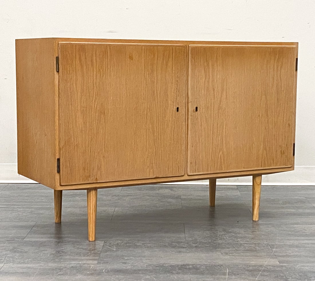 CARLO JENSEN FOR POUL HUNDEVAD DANISH OAK CABINET: Two-door cabinet. Includes key. Apparently unmarked. Denmark, circa 1960s. Dimensions: H 27" x W 42.5" x D 17" Condition: Wear consistent with age and use. Fading, scuffs. minor soiling spots. Light d
