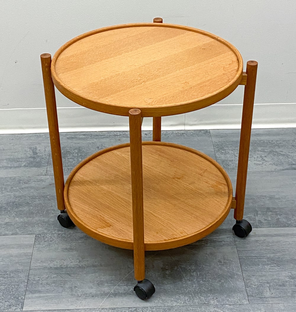STYLE OF HANS BOLLING DANISH TRAY TABLE C. 1970S: Removable circular tray shelves and casters. In teak. Denmark, circa 1970s. Dimensions: H 23" x Dia 23" Condition: Wear consistent with age and use. Scuffs, rubs, fading, soiling to trays.