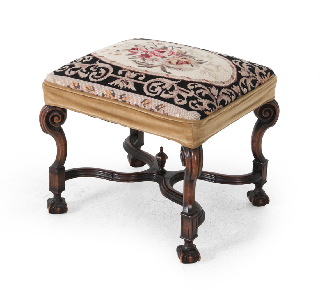ANTIQUE BAROQUE STYLE WALNUT FOOTSTOOL: Carved walnut base with stretcher joined legs. Floral needlepoint seat with velvet trim. mid to late 19th century. Dimensions: H 19" x W 21.5" x D 18.5" Condition: Scuffs and wear of finish. Wear