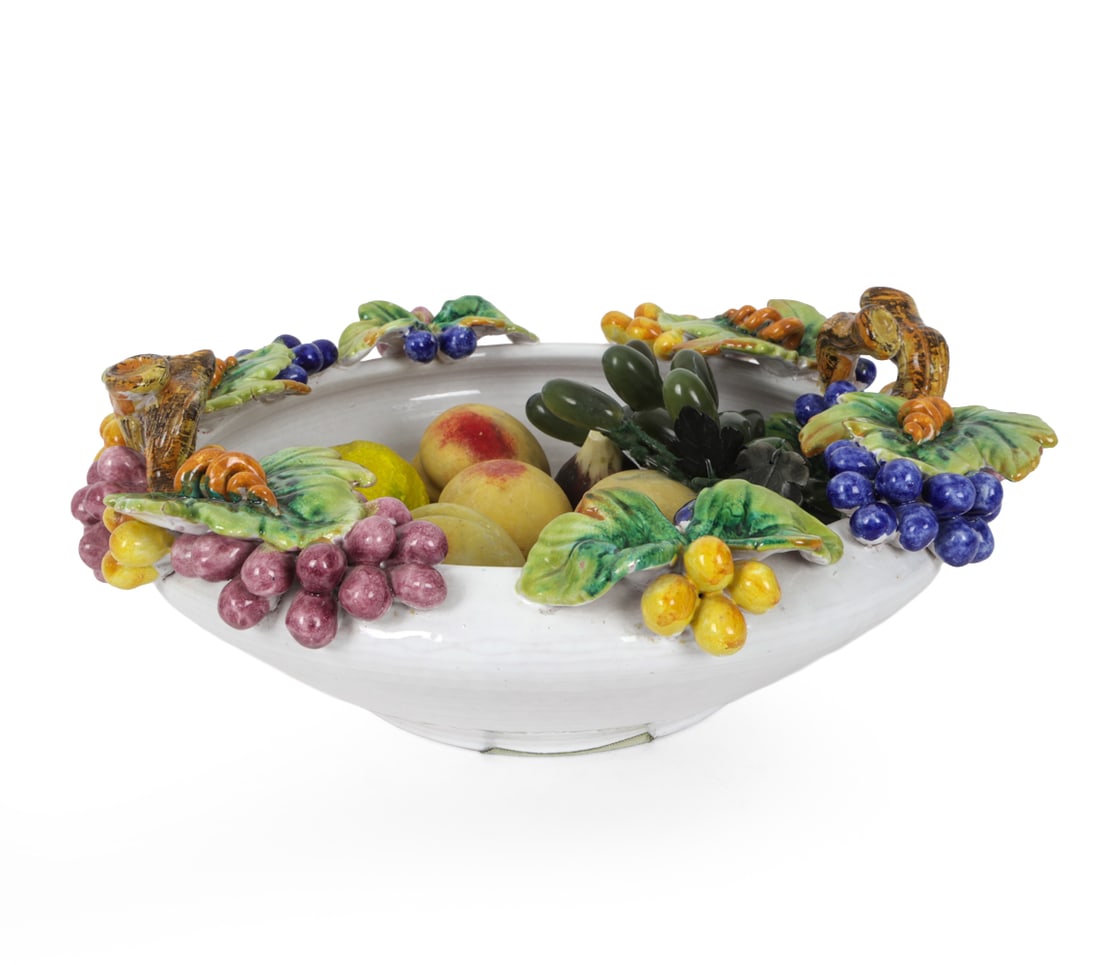 CERAMIC FRUIT BOWL AND STONE FRUIT: Includes (4) peaches, pair of figs, lime, and bowl. Ceramic bowl decorated with fruit in high relief. Made in the style of Italian Majolica. Dimensions: H 7" x W 16.5" x D 16" Condition: Evidence of p