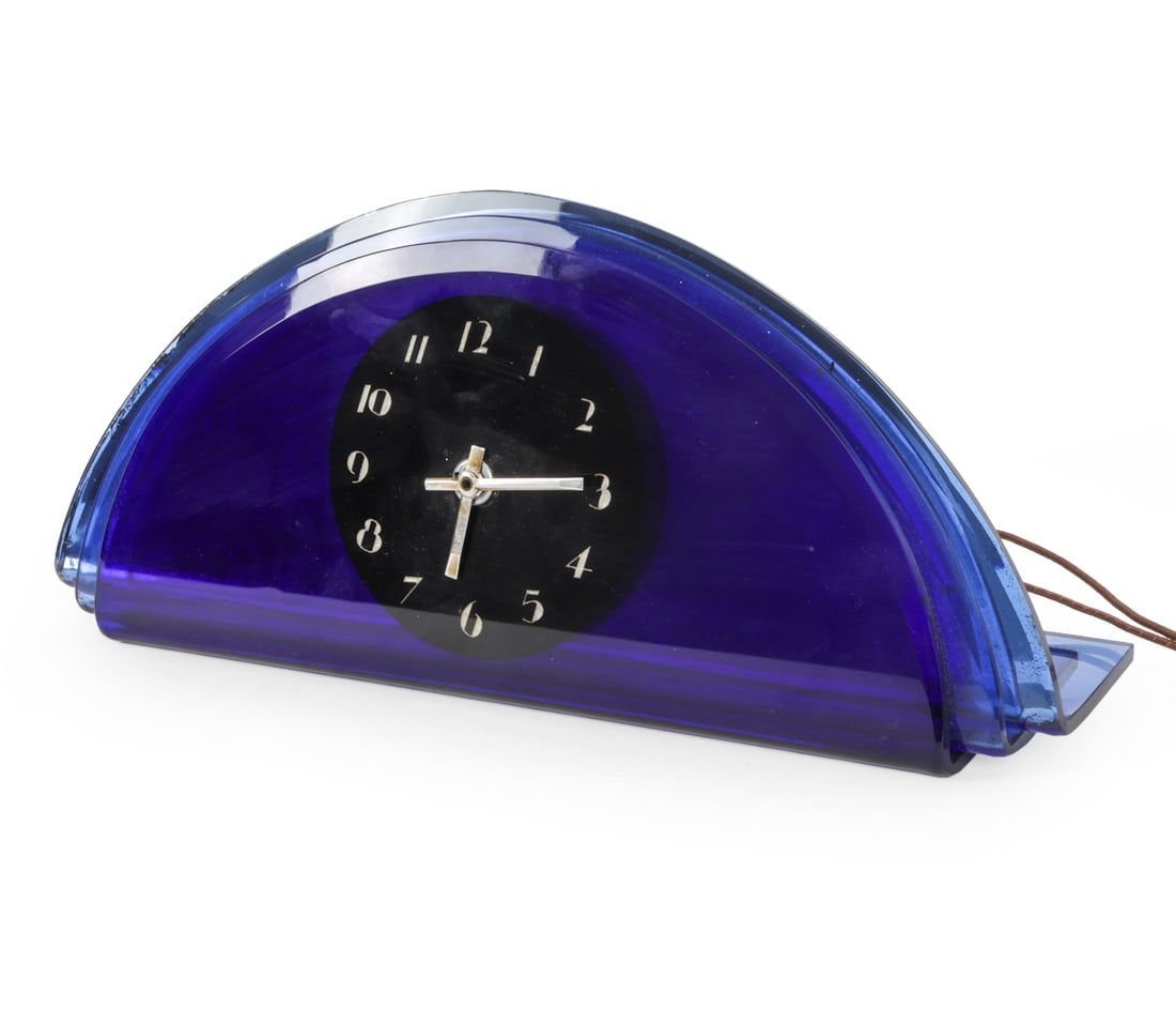 WALTHAM ART DECO LAYERED GLASS CLOCK: Waltham Watch Co. art deco electric desk clock, circa 1930s. Cobalt blue glass case with black Arabic numeral dial on mirrored metal base. Labeled verso. Dimensions: H 7" x W 15.5" x D 4" Condition: S