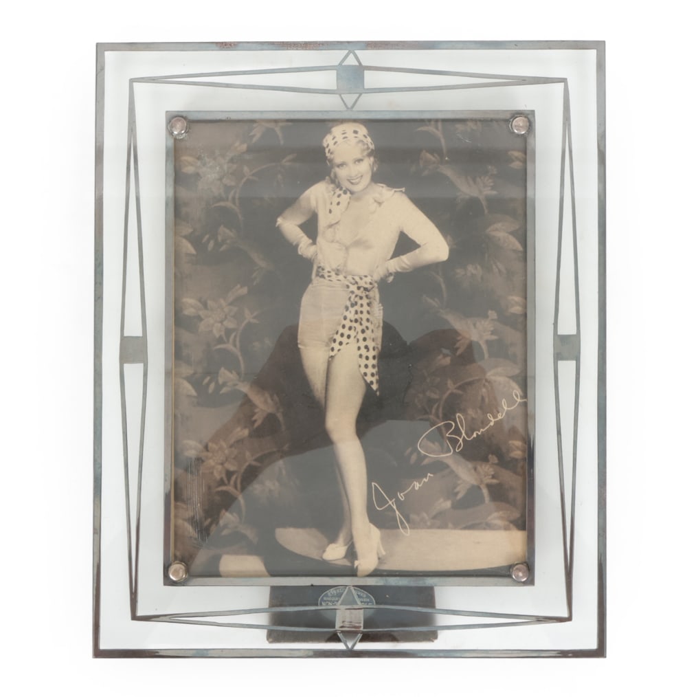 JOAN BLONDELL PHOTOPRINT DECO SILVER OVERLAY FRAME: Joan Blondell photo print. Frame labeled on back stand. Features sterling silver overlay. Circa 1930s. Dimensions: (frame) H 12" x W 10" (sight) H 9" x W 7" Condition: Wear consistent with age and use