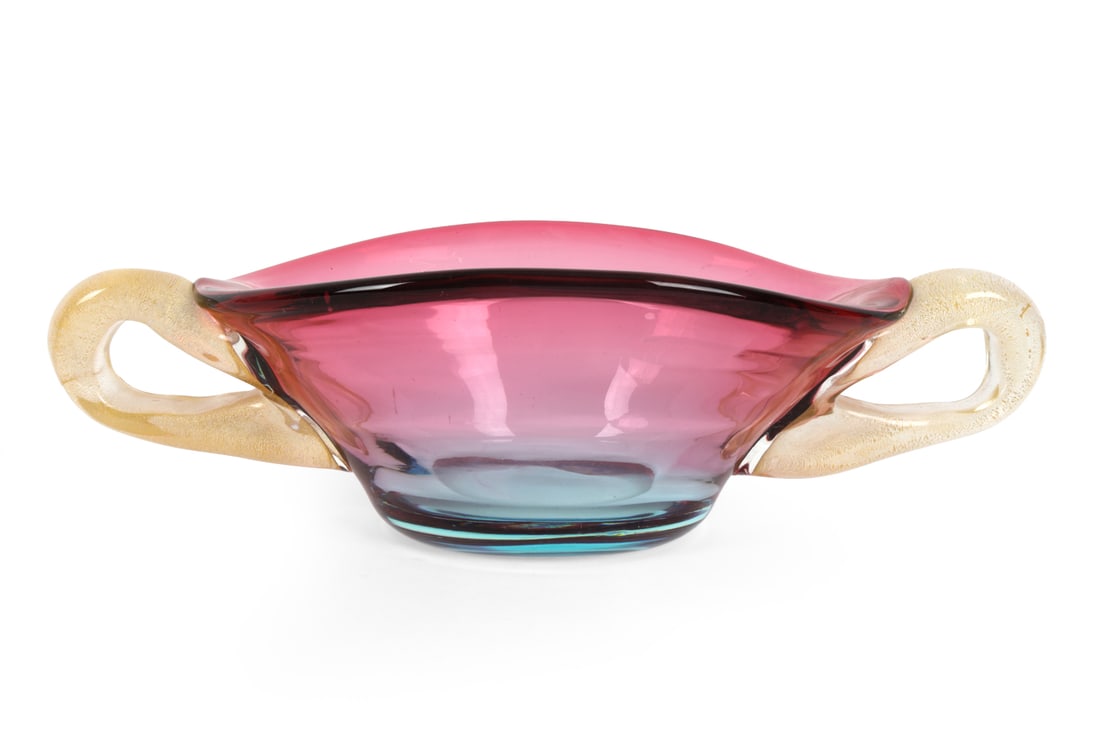 MID-CENTURY MURANO GLASS CENTERPIECE BOWL: Murano glass bowl in pink and blue with handles. Dimensions: H 4.5" x W 16" x D 8" Condition: Scratches, fleabites to surface. Wear consistent with age and use.