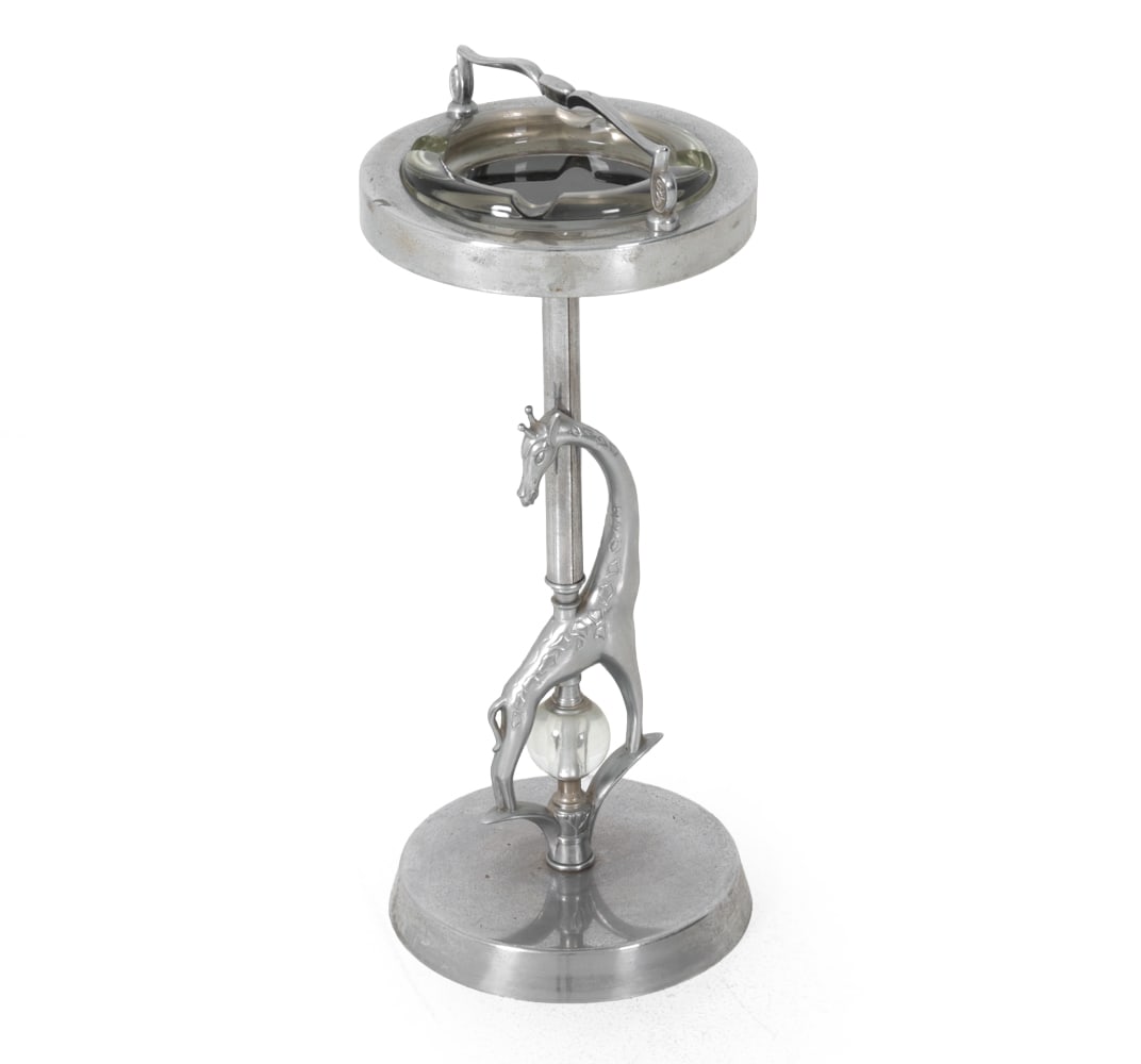 ART DECO GIRAFFE SMOKING STAND C. 1940S: Metal frame with glass removable ashtray and giraffe detail at base. Circa 1940s. Dimensions: H 25" x Dia 10.5 " Condition: Surface marks, scuffs, some patina. Wear consistent with age and use.