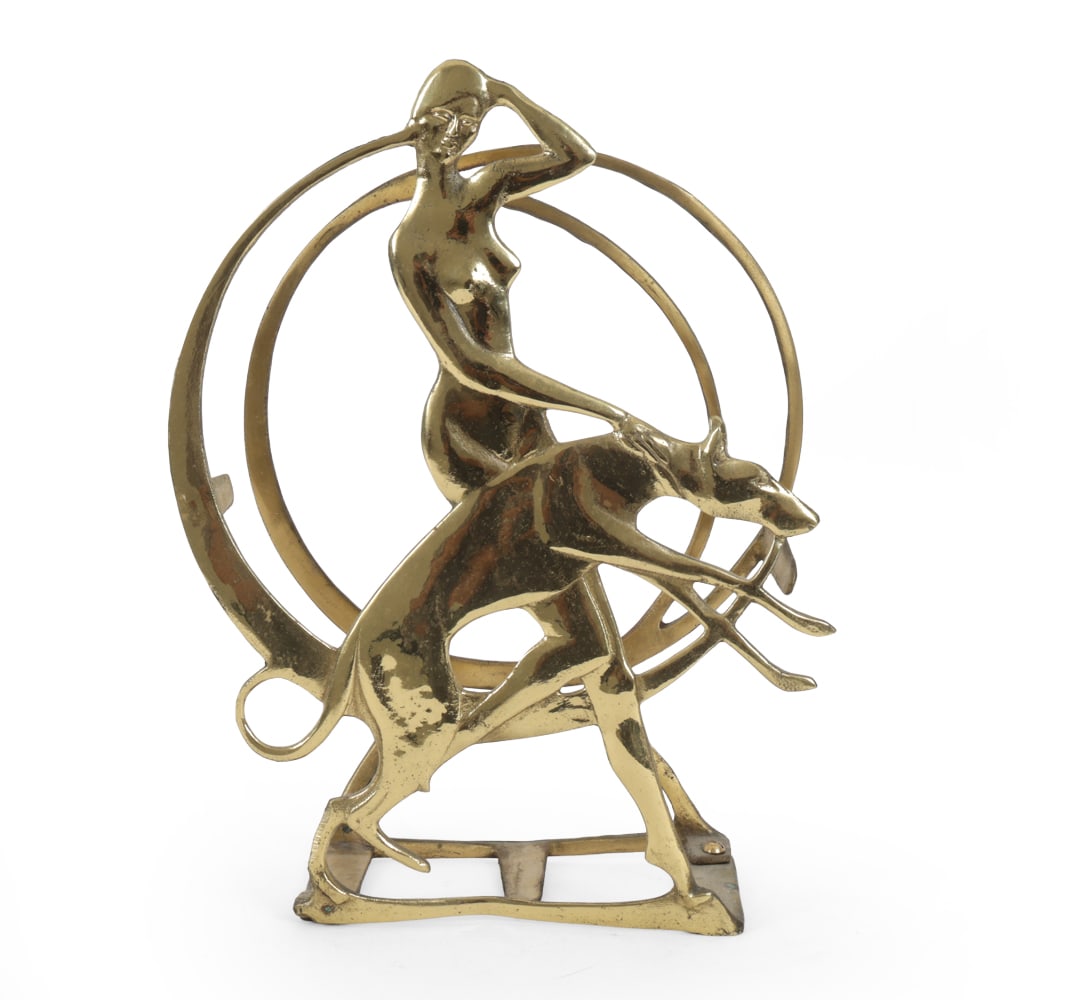 ART DECO LADY & DOG BRASS MAGAZINE RACK C. 1930S: Brass nude woman holding dog. circa 1930s. Dimensions: H 16 " x W 4.5 " x D 12 " Condition: Wear consistent with age and use, including patina and some scuffs.