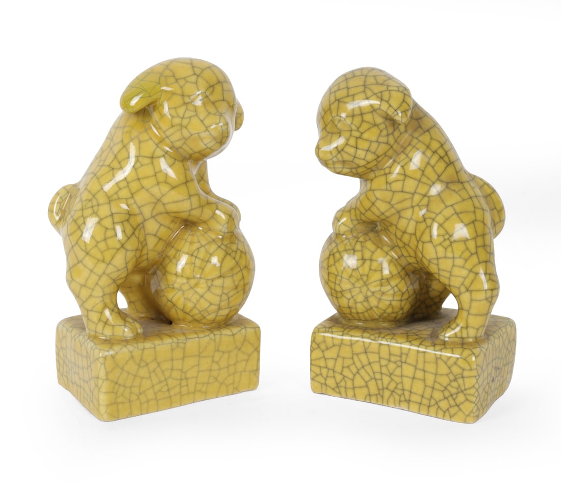 PAIR OF JAPANESE PORCELAIN DOG BOOKENDS C. 1920S: Pair of porcelain crackle glaze yellow dog bookends. Japan, circa 1920s. Dimensions: H 7" x W 4.25" x D 3" Condition: Natural crazing. Wear consistent with age and use. Minor discolored areas.