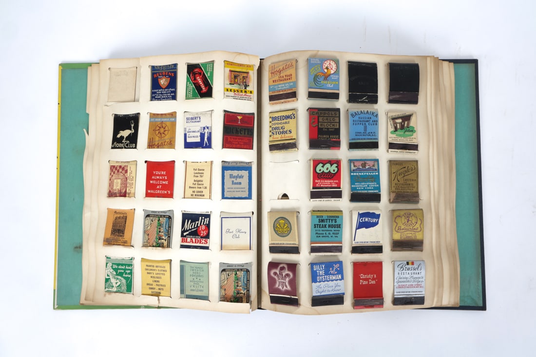 VINTAGE MATCHBOOK COLLECTION: Cardboard book with paper pages with slots for matchboxes. Both books are filled with matchboxes. Circa 1930s. Dimensions: H 13.25" x W 10.25" Condition: Wear to finish, scuffs, and tears in interior 