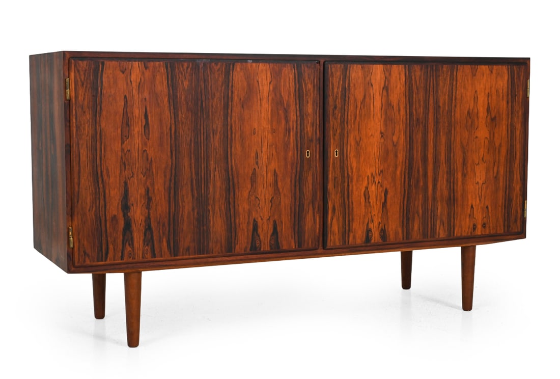 POUL HUNDEVAD ROSEWOOD SIDEBOARD C. 1960S: Rosewood with tapered legs and interior storage. Drawers inside are lined with green felt. Key included. Denmark, circa 1960s. Dimensions: H 30'' x W 55'' x D 17" Condition: A few scuffs and stains, l