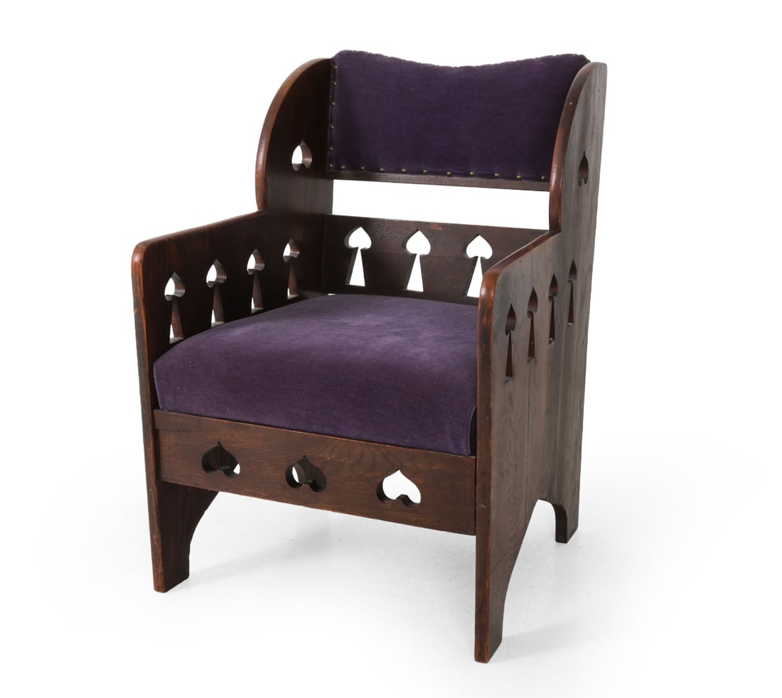 ARTS & CRAFTS OAK CUTOUT ARM CHAIR: Oak frame with spade and heart cutout pattern and velvet cushions. Early 20th century. Dimensions: H 33" x W 23" x D 22.5" x SH 17" Conditions: Showing signs of wear consistent with age and use, scuff