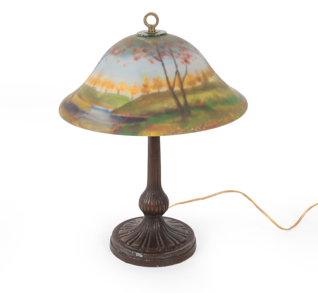 ARTS & CRAFTS STYLE REVERSE PAINTED SHADE LAMP: Reverse painted forest scene lampshade with painted white metal base. Dimensions: (lamp) H 16.75" x W 6.75" (shade) H 6" x W 13.25" Condition: Wear of finish and scuffs on base. Untested. Wear