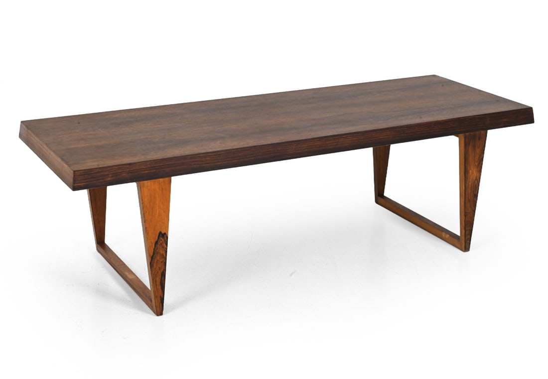 MOGENSEN STYLE DANISH ROSEWOOD COFFEE TABLE: Rosewood coffee table with sharp-angled sled legs. Denmark, circa 1960s. Dimensions: H 20'' x W 66'' x D 24" Condition: Showing signs of wear including chip, veneer loss to one top corner. Previous re