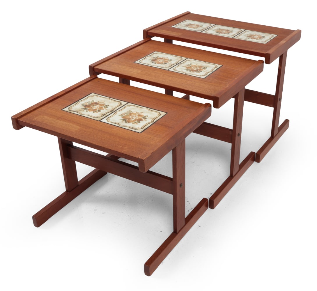 DANISH TEAK & TILE NESTING TABLES C. 1960S: (3) teak nesting tables with inset floral ceramic tile tops. Denmark, Circa 1960s. Dimensions: (Largest) H 19.5" x W 23.5?x D 15.75? Condition: Water stain to top, slight dent to top edges. Some rubs 