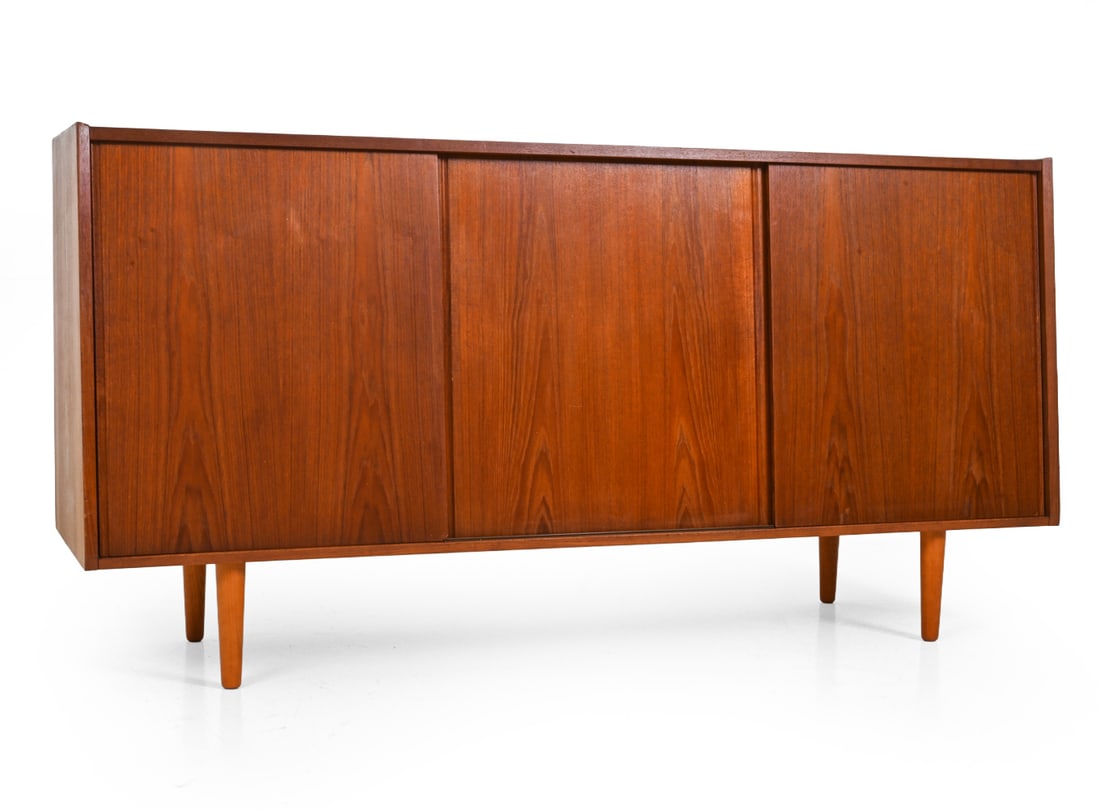 E. W. BACH STYLE DANISH TEAK SIDEBOARD C. 1960S: Mid Century teak sideboard with raised edge. Interior fitted with adjustable shelving. Denmark, circa 1960s. Dimensions: H 34" x W 67" x D 19" Condition: Scuffs, fading and discoloration. Loss to fron