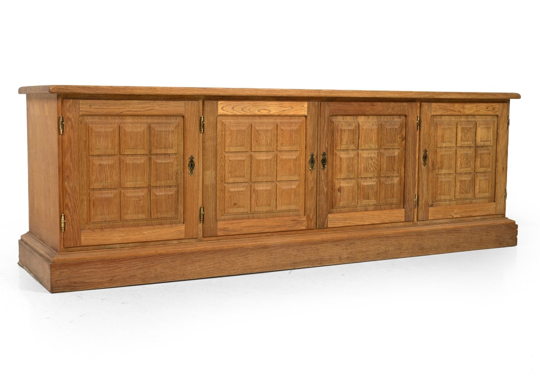 KJAERNULF STYLE DANISH OAK SIDEBOARD C. 1960S: Key included. paneled doors and brass hardware. In oak. Denmark, circa 1970s. Dimensions: H 25.5'' x W 75.5'' x D 19.5" Condition: Wear consistent with age and use, small veneer losses to base. Waterm