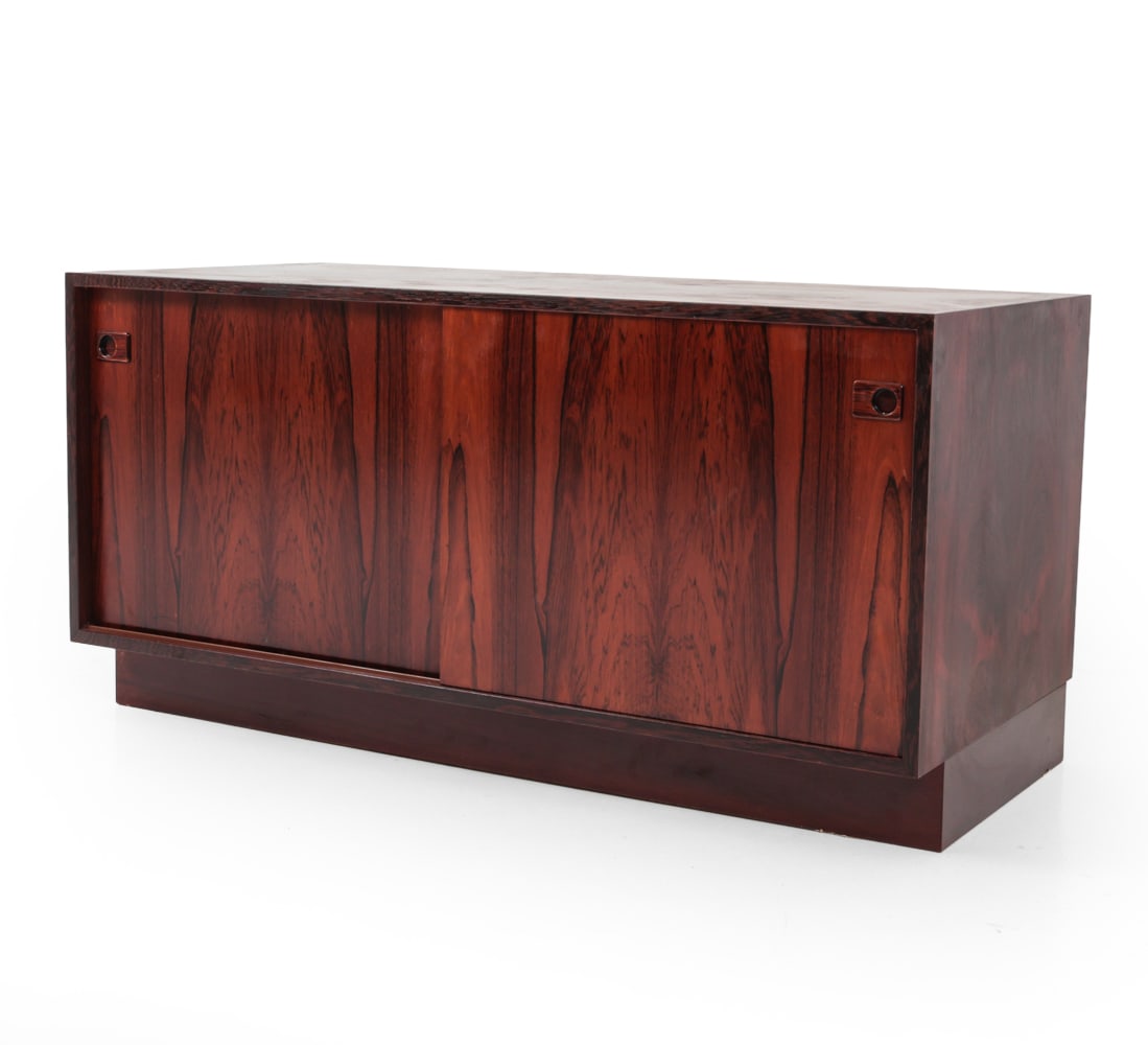 HUNDEVAD STYLE DANISH ROSEWOOD CABINET C. 1960S: Recessed handles with sliding doors and interior shelves. Danish furniture stamp on backside. Dimensions: H 21.5" x W 43.25" D 20" Condition: Some sun fading and scratches. Wear consistent with age an