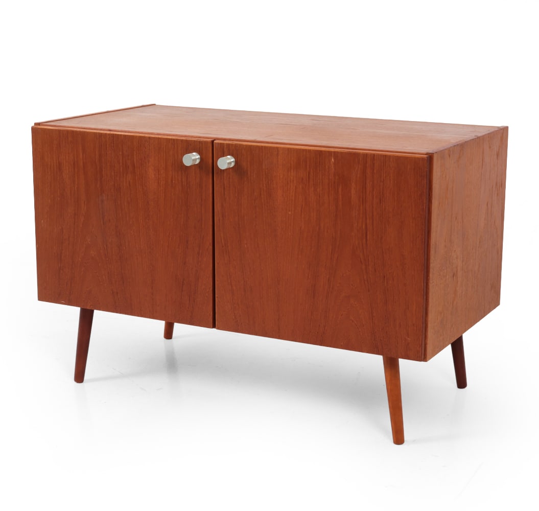 MID-CENTURY DANISH TEAK CABINET C. 1960S: Teak two door cabinet with aluminum knobs and interior shelves. Denmark, circa 1960s. Dimensions: H 25.5" x W 39.5" x D 20.5" Condition: Few scratches to top. Sun fading. Wear consistent with age and 